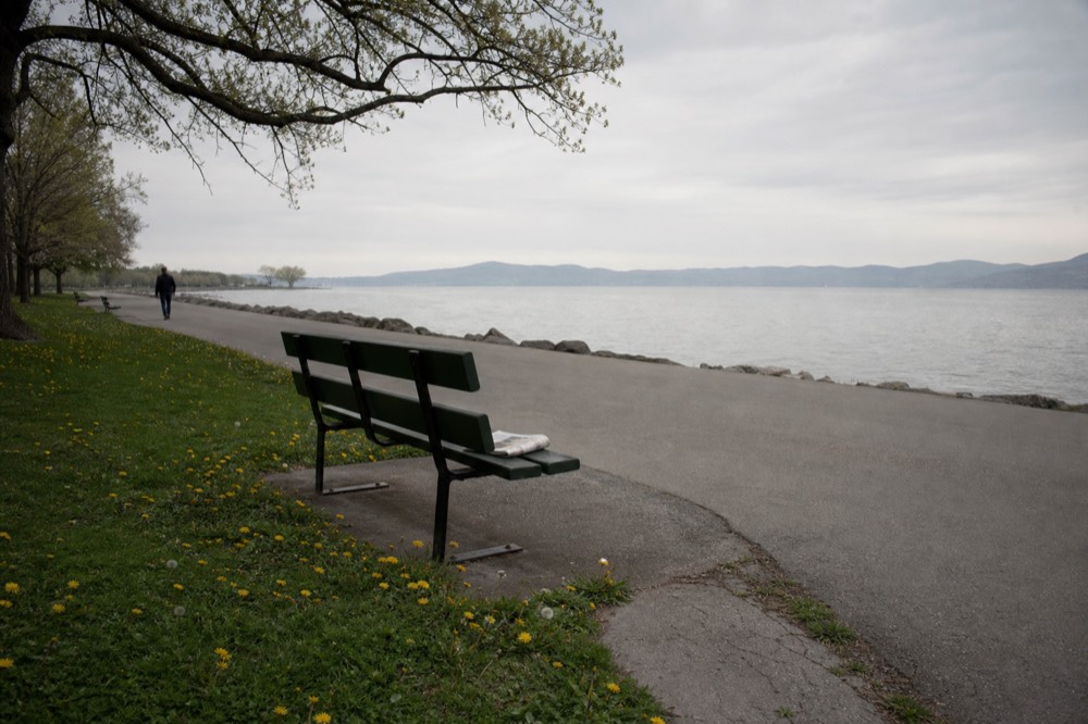 A lakefront promenade with park lawns and hills across the water, no text, no logos, no people