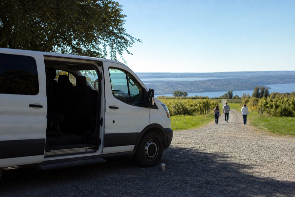 A small van parked at a winery entrance above Seneca Lake, no text, no logos, no people