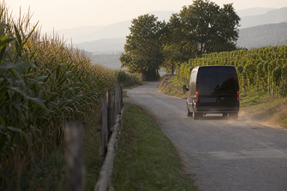 A private van on a rural road between vineyards, no text, no logos, no people