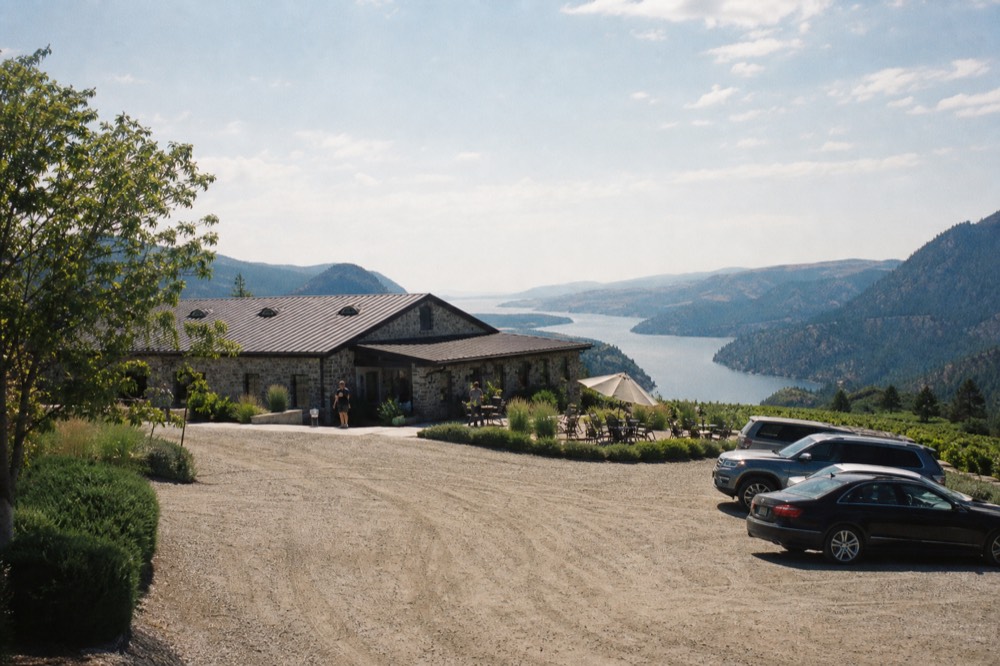 Winery perched on a hillside above a long narrow lake, no text, no logos, no people