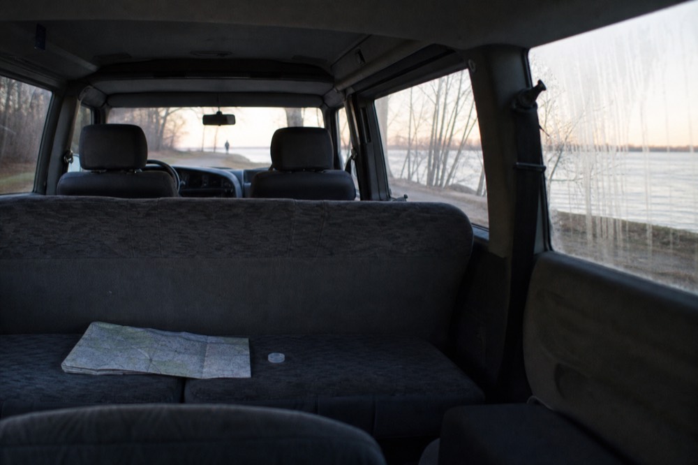 A private van interior with empty seats and a view of lake shoreline through the windows, no text, no logos, no people