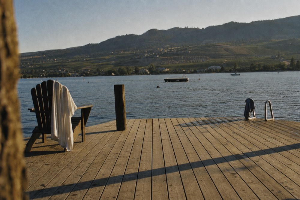A dock and lake in late afternoon light, hills and vineyards in the distance, no text, no logos, no people
