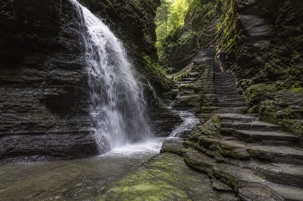 Waterfall cascading through a mossy gorge with stone steps alongside, no text, no logos, no people