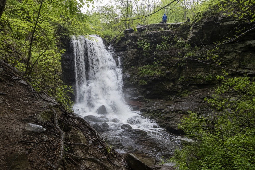 A waterfall in a wooded gorge near a lakeside town, no text, no logos, no people