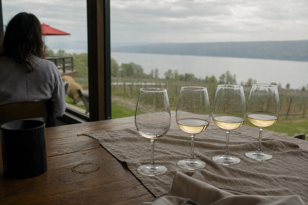 Table set for a wine tasting flight overlooking a lake, no text, no logos, no people