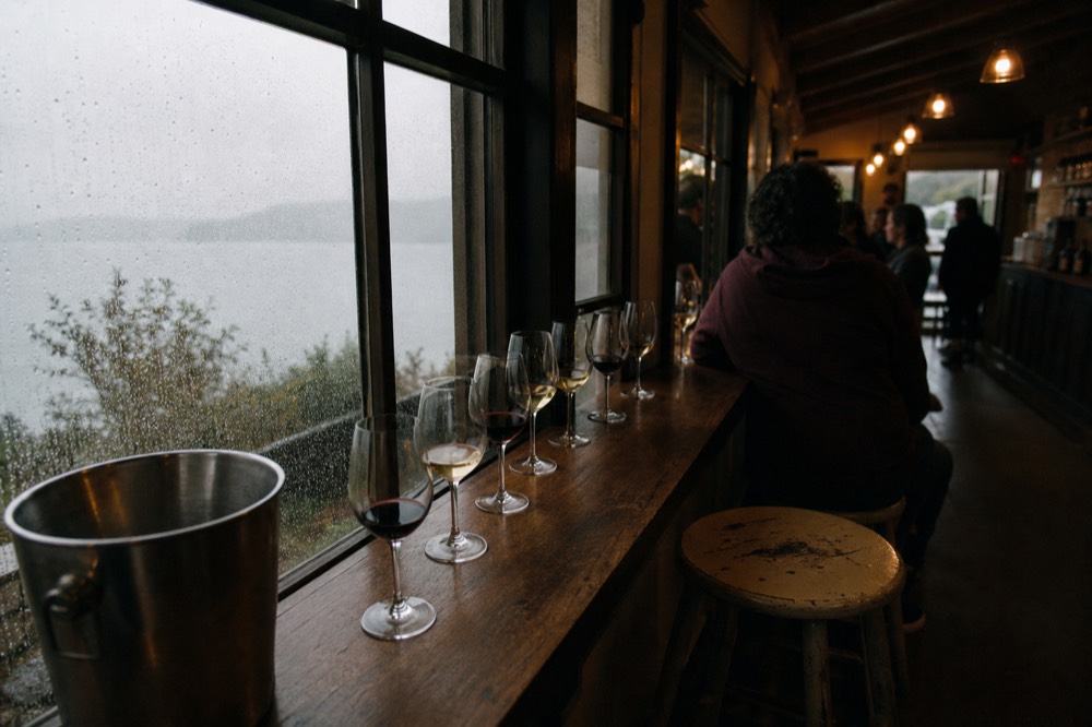 Small tasting room bar with wine glasses lined up by a window, no text, no logos, no people