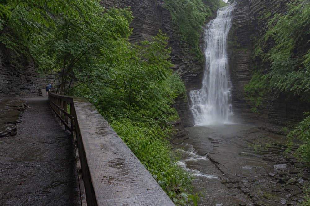 A waterfall dropping into a rocky gorge near a college town, no text, no logos, no people