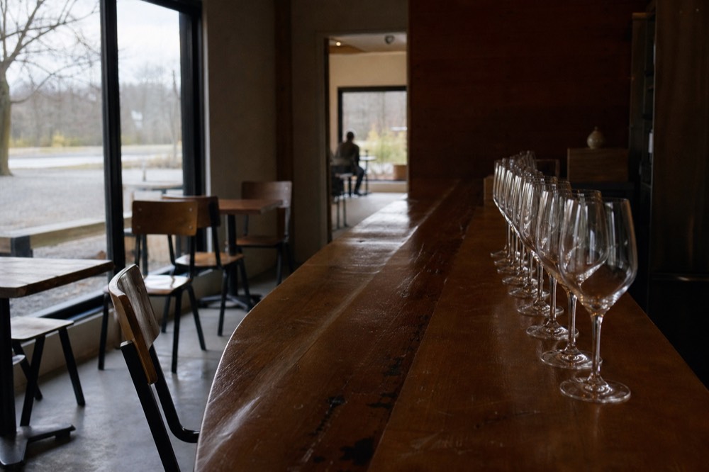 A quiet tasting bar with empty stemmed glasses waiting before opening, no text, no logos, no people.